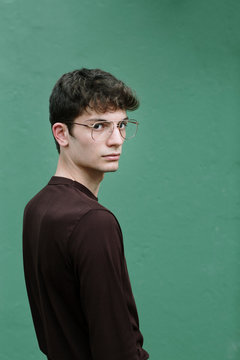 Serious young man looking at camera on green background