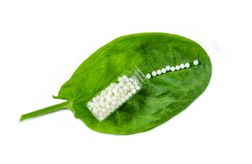 Homeopathy - A homeopathy concept with homeopathic medicine on green leaves
