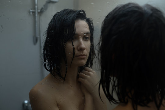 Woman in shower looking at mirror