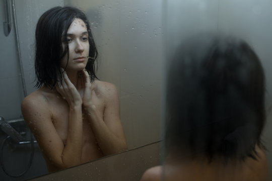 Woman in shower looking at mirror