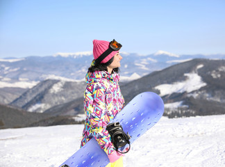 Young woman with snowboard outdoors. Winter vacation