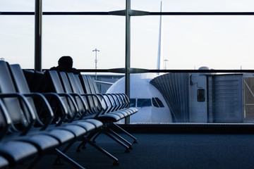 Empty row of seats in waiting area at airport with airplane on background. Futuristic look of...