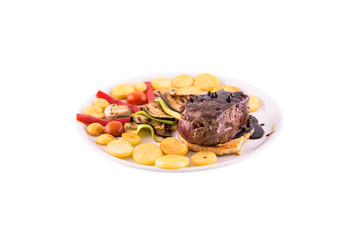 Fried beef on the bone. The garnish is served with fried potatoes with eggplant. Photo taken on a white background. Dish of Montenegrin cuisine. Suitable for the restaurant menu.