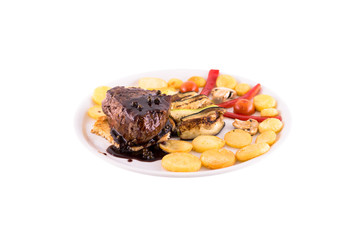Fried beef on the bone. The garnish is served with fried potatoes with eggplant. Photo taken on a white background. Dish of Montenegrin cuisine. Suitable for the restaurant menu.