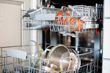 some dirty dish tableware on the tray in dishwasher machine in the kithcen