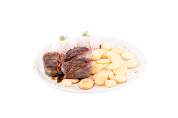 Ham meat medallions. Boiled rice and fried potatoes are served on the side dish. Photo taken on a white background. Dish of Montenegrin cuisine. Suitable for the restaurant menu.