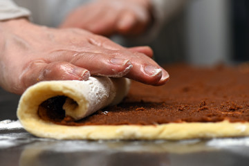 Rolling homemade cinnamon buns by hand closeup macro