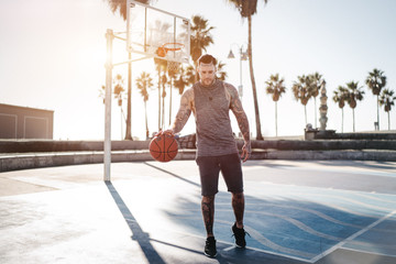 Junger Tätowierter Mann spielt Basketball im Gegenlicht - 333014514
