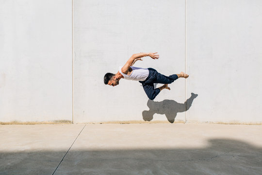 A dancer dancing in front of a concrete wall