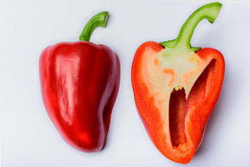 Two halves of red sweet pepper one of them turned inside out on a white background.