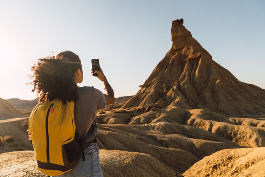 Back view of female traveler using mobile camera for taking picture of Castil de tierra landscape