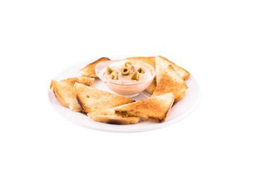 Heated bread (toast) with cream sauce and green olives. Served on a white plate. Photo taken on a white background. Dish of Montenegrin cuisine. Suitable for the restaurant menu.
