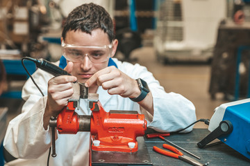 student of technical school on practical exam when working with vise and electric grinder