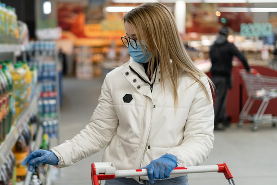 young woman wearing a mask and gloves buying in a supermarket. Panic purchases during the Coronavirus covid-19 pandemic. Buying a budget at a supply store.
