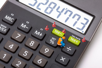 Conceptual image of a miniature figure workman next to buttons marked tax