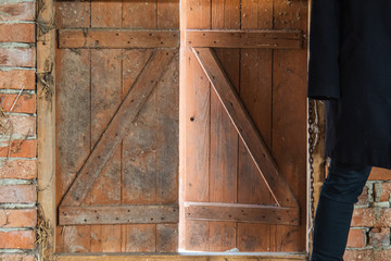 Stylish woman standing near old brick wall in the background and half-open door
