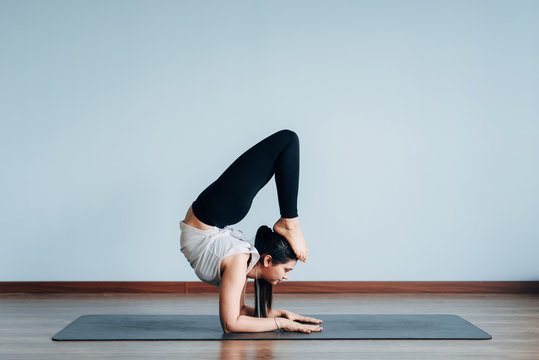 Pretty sporty Indian woman doing difficult yoga pose