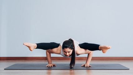 Pretty sporty Indian woman doing difficult yoga pose