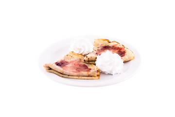 Pancakes with fruit jam, butter cream and nuts. Served on a white plate, melted on a white background. The photo is suitable for feeding mei restaurant. Dish of Montenegrin cuisine.