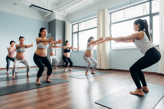 Prenatal yoga class, pregnant women doing yoga with instructor in class