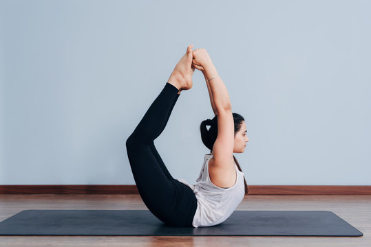 Pretty sporty Indian woman doing difficult yoga pose
