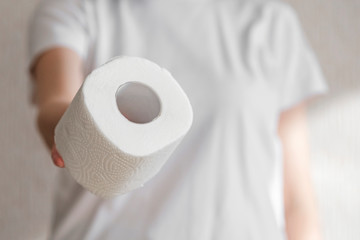 The girl shares toilet paper and holds out the roll forward.People are stocking up toilet paper for home quarantine from crownavirus. preparation for quarantine and economic crisis due to coronavirus.