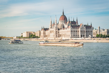 Fototapeta na wymiar The Budapest Parliament at sunset. Boats passing by on Danube river, Hungary 2019