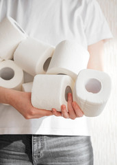 People are stocking up toilet paper for home quarantine from crownavirus. Woman holds many rolls of toilet paper. preparation for quarantine and economic crisis due to coronavirus. Hygiene concept
