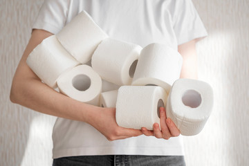 People are stocking up toilet paper for home quarantine from crownavirus. Woman holds many rolls of toilet paper. preparation for quarantine and economic crisis due to coronavirus. Hygiene concept