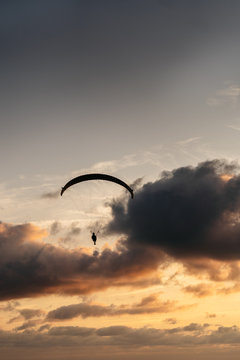 Silhouette of anonymous paraglider flying at sunset