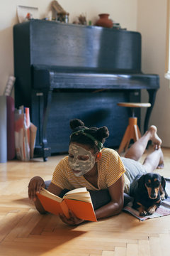 Woman reading a book, spending time with her small black dog ind