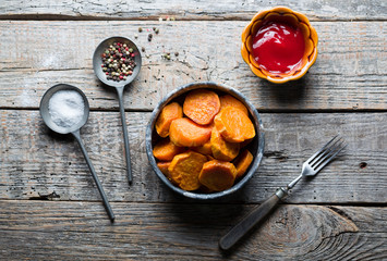 Delicious fried sweet potatoes on the wooden background.