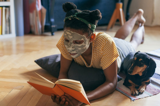 Woman reading a book, spending time with her small black dog ind