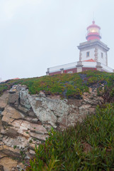 Fototapeta na wymiar The lighthouse at Cape Cabo da Roca on a foggy day. A view of the rock and the lighthouse from bottom to top.