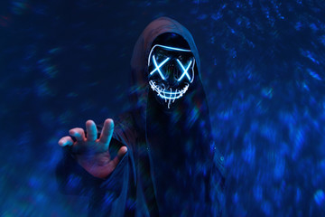 Dangerous hooded hacker. Internet, cyber crime, cyber attack, system breaking and malware concept. Anonymous. Dark background.