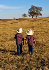 Naklejka na ściany i meble Two Little Cowboys Heading Out Across A Pasture in South Central Oklahoma to Check on the Calves