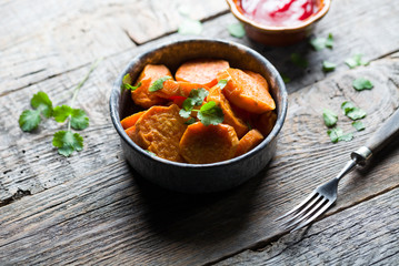 Delicious fried sweet potatoes on the wooden background.