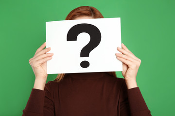 Woman holding question mark sign on green background