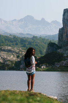 Happy brown skinned woman standing on a lake at Covadongas, in Europe Peaks in Asturias