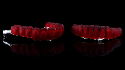dental wax-up dentures with red wax crowns on a black background with reflection