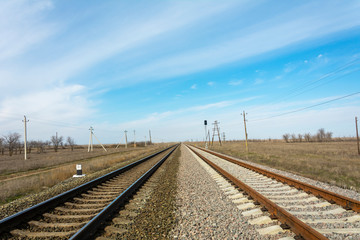 Fototapeta na wymiar The old dark railway and in parallel with it a new fresh railway, the rails go into the distance beyond the horizon. Bright blue sky background. The concept of the past and the future is close.