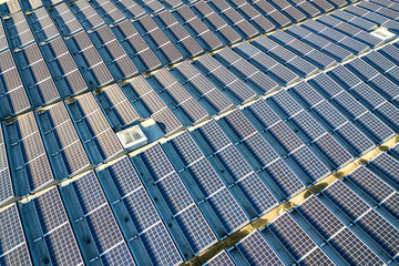 Aerial view of many photo voltaic solar panels mounted of industrial building roof.