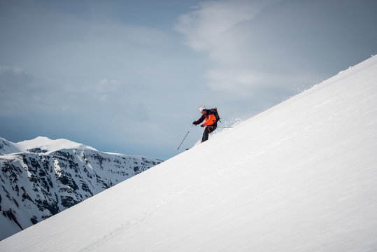 Man skiing downhill in Iceland with mountains behind