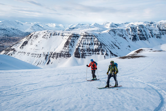 Man and woman skiing in Iceland with mountains in background