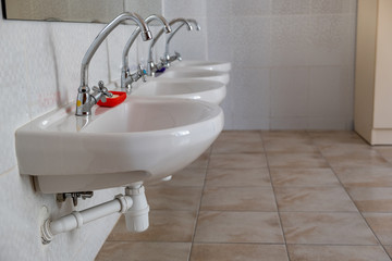 White ceramic washing basins with shiny stainless steel water tap.