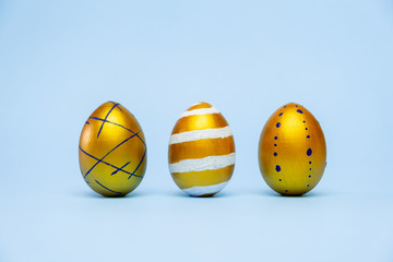Happy Easter. Three easter eggstrendy colored classic blue, white and golden on blue background. Copy space. Minimal style