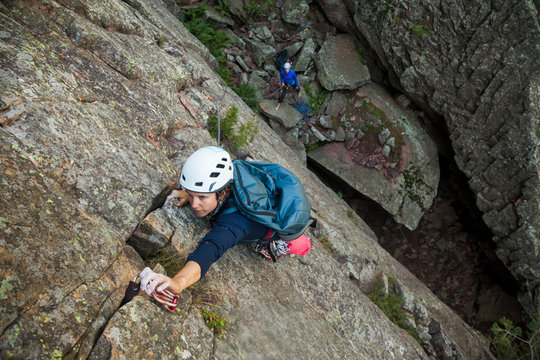 Woman rock climbs Matron North Face, Flatirons near Boulder, Colorado