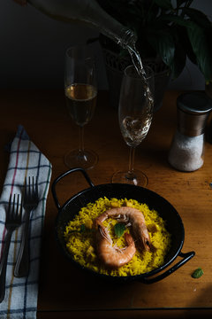 a plate of Spanish paella prepared for two accompanied by two glasses