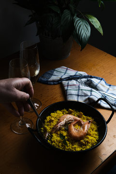 a plate of Spanish paella prepared for two accompanied by two glasses