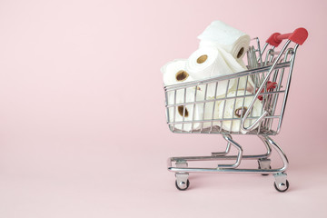 Consumer panic corona virus concept. Toilet paper rolls in shopping cart abstract on pastel pink...